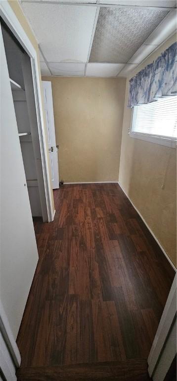 corridor featuring a paneled ceiling and dark hardwood / wood-style flooring