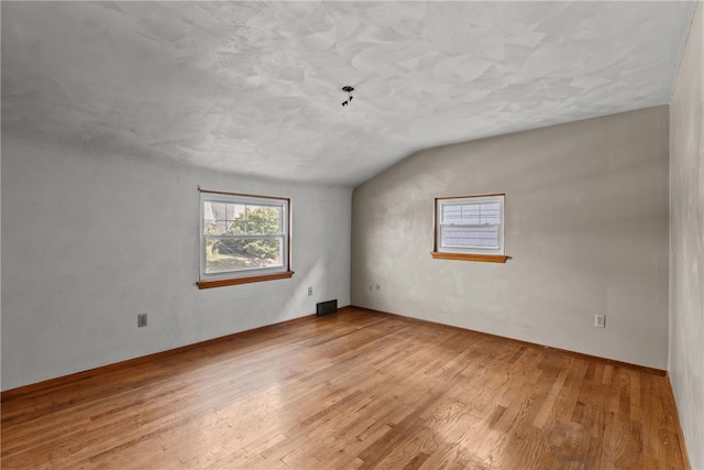 spare room with lofted ceiling and light hardwood / wood-style floors