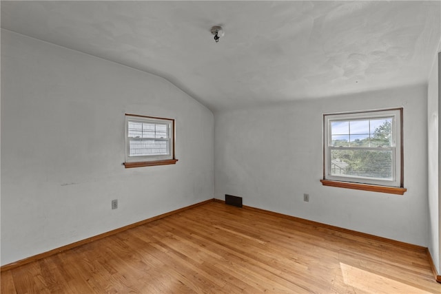 spare room with light hardwood / wood-style flooring and lofted ceiling