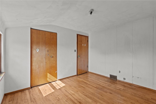 unfurnished bedroom featuring vaulted ceiling and light wood-type flooring