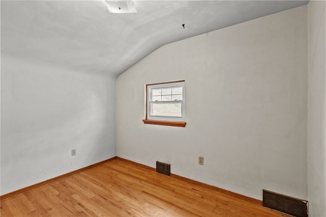 empty room featuring vaulted ceiling and light wood-type flooring