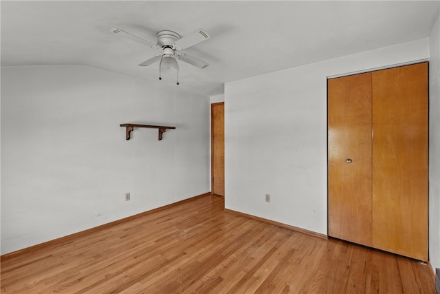 unfurnished bedroom with a closet, lofted ceiling, ceiling fan, and light wood-type flooring