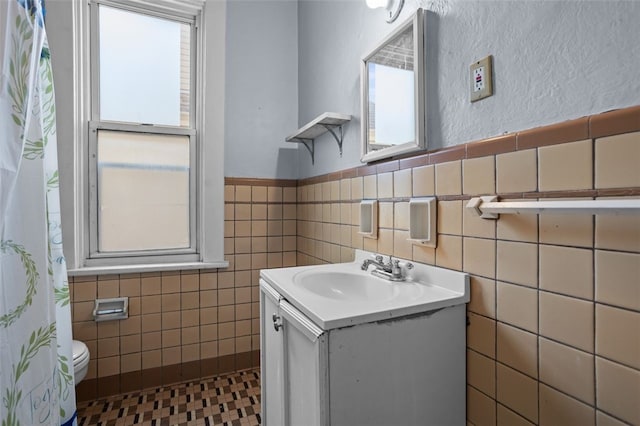 bathroom with toilet, tile walls, and vanity