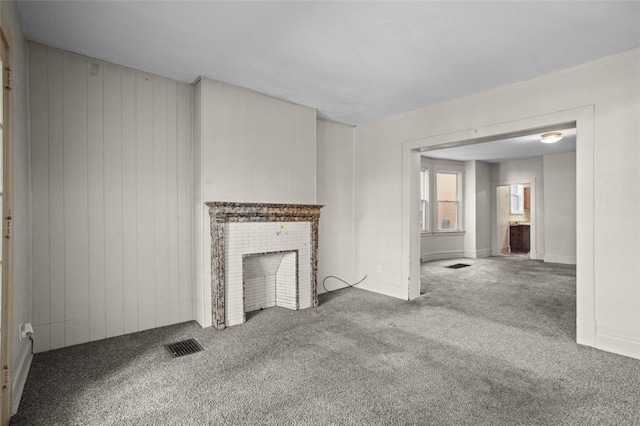 unfurnished living room featuring a brick fireplace and carpet flooring