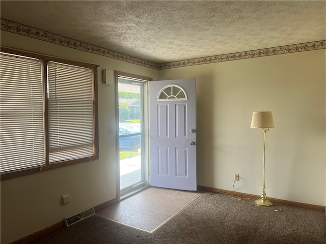 entrance foyer with a textured ceiling, carpet floors, and plenty of natural light