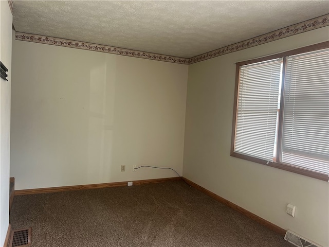 carpeted empty room featuring a textured ceiling