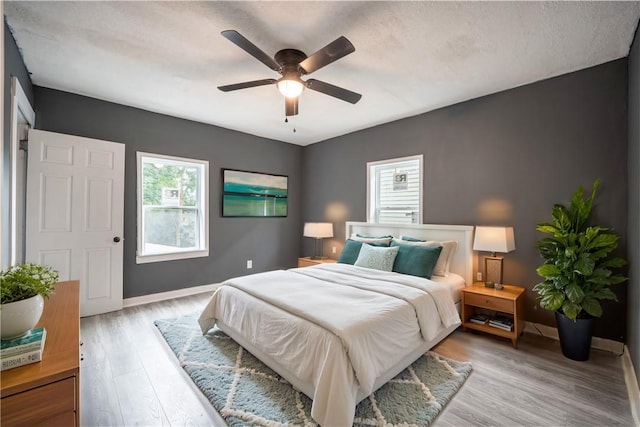 bedroom featuring ceiling fan, light hardwood / wood-style floors, and a textured ceiling