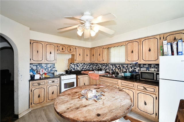 kitchen with light hardwood / wood-style flooring, ceiling fan, backsplash, and white appliances