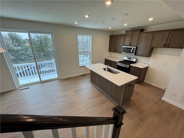 kitchen featuring sink, stainless steel appliances, light hardwood / wood-style flooring, a kitchen island with sink, and dark brown cabinets