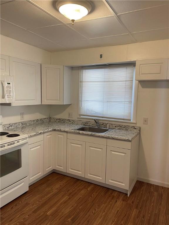 kitchen featuring white appliances, dark wood-type flooring, a sink, white cabinets, and light stone countertops