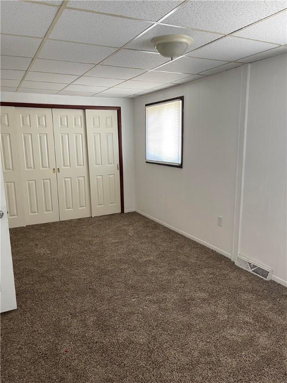 unfurnished bedroom featuring a drop ceiling and carpet flooring