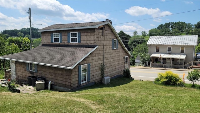 rear view of property featuring central AC unit and a yard