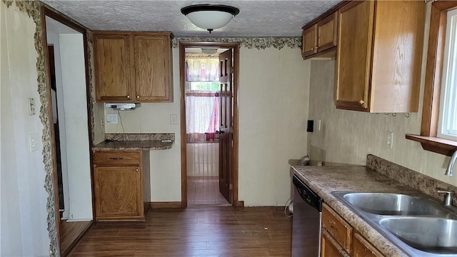 kitchen with dark hardwood / wood-style floors, dishwasher, sink, and a textured ceiling