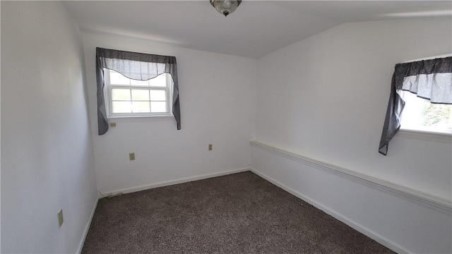 empty room featuring lofted ceiling and dark carpet