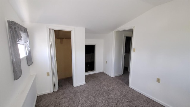 unfurnished bedroom featuring dark colored carpet, vaulted ceiling, and a closet