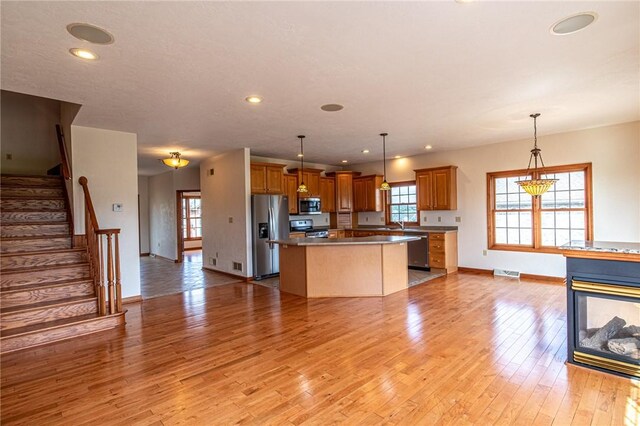 kitchen with a center island, decorative light fixtures, light hardwood / wood-style flooring, and appliances with stainless steel finishes