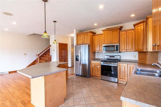 kitchen with a kitchen island, stainless steel appliances, light hardwood / wood-style floors, hanging light fixtures, and sink