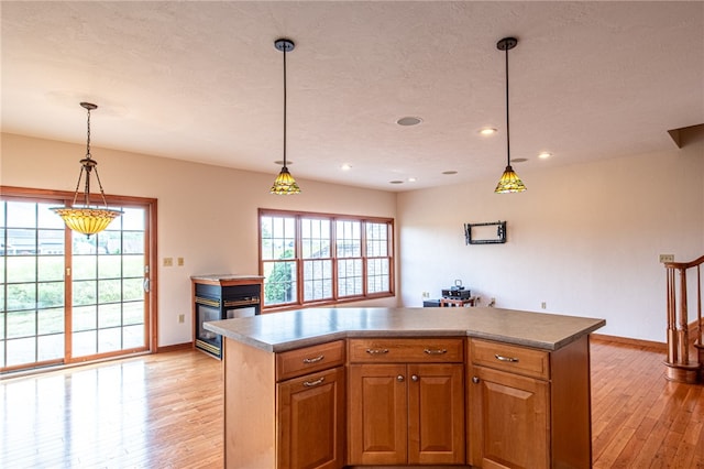 kitchen with a center island, light wood-type flooring, and decorative light fixtures