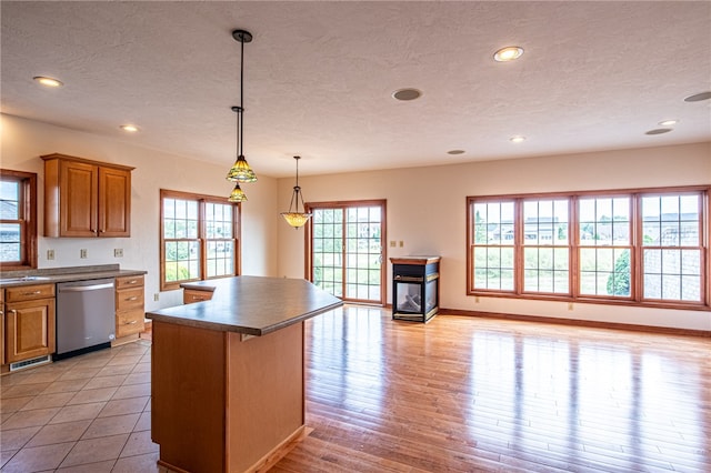 kitchen with light hardwood / wood-style floors, dishwasher, a textured ceiling, and a center island