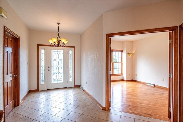 foyer with light tile patterned flooring and an inviting chandelier