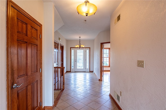 hall with an inviting chandelier and light tile patterned floors