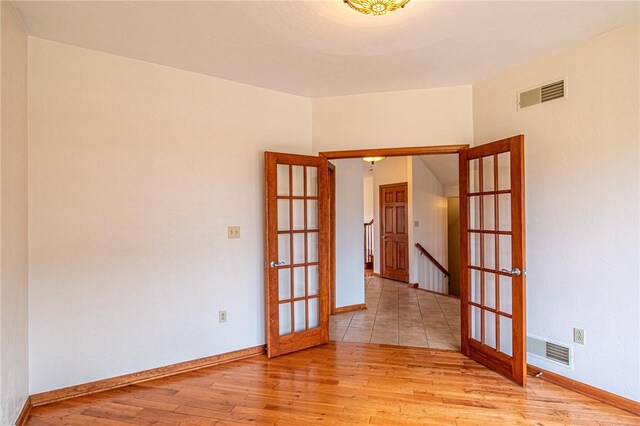 empty room with light hardwood / wood-style flooring and french doors