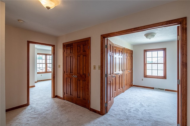 hall featuring plenty of natural light and light colored carpet