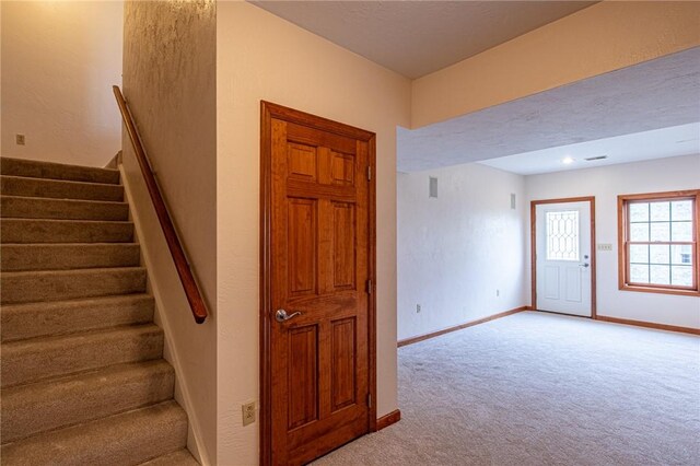 staircase featuring light colored carpet