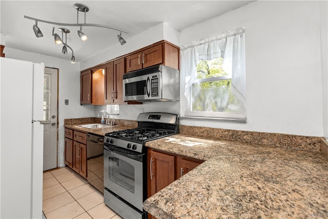 kitchen featuring light tile patterned flooring, sink, dark stone countertops, appliances with stainless steel finishes, and track lighting