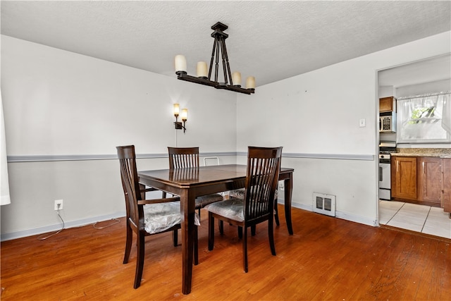 dining room featuring a notable chandelier, a textured ceiling, and light hardwood / wood-style floors