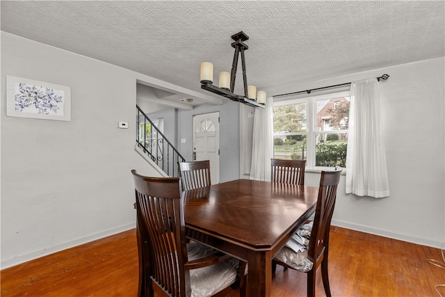 dining area with a notable chandelier, a textured ceiling, and hardwood / wood-style floors