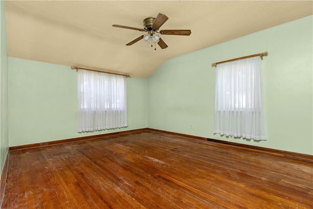 spare room with ceiling fan, vaulted ceiling, a textured ceiling, and hardwood / wood-style flooring