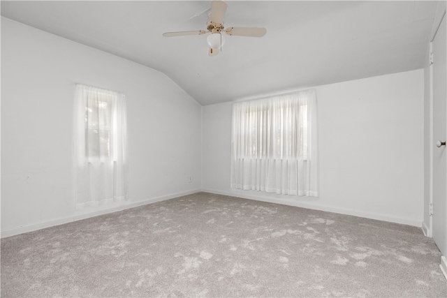 carpeted spare room featuring ceiling fan and vaulted ceiling