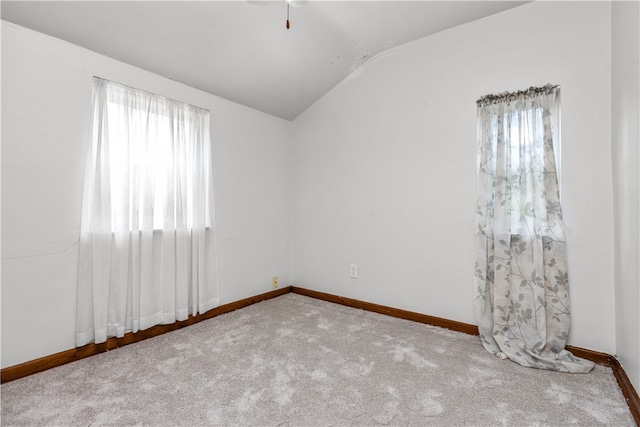 carpeted spare room featuring a wealth of natural light and vaulted ceiling