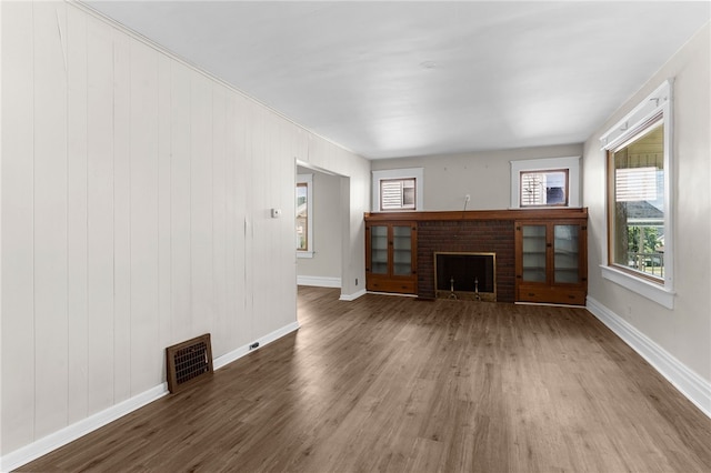 unfurnished living room featuring a brick fireplace and wood-type flooring