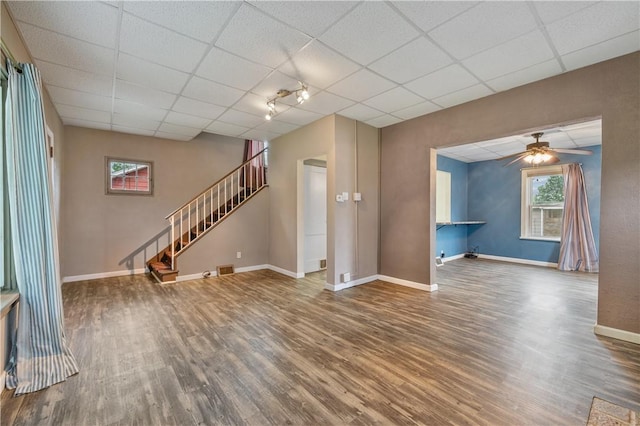 unfurnished living room featuring ceiling fan, rail lighting, a drop ceiling, and hardwood / wood-style floors