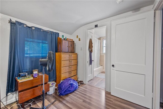 bedroom featuring hardwood / wood-style flooring, lofted ceiling, and ensuite bath