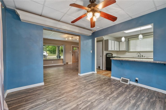 kitchen with a drop ceiling, pendant lighting, wood-type flooring, and ceiling fan