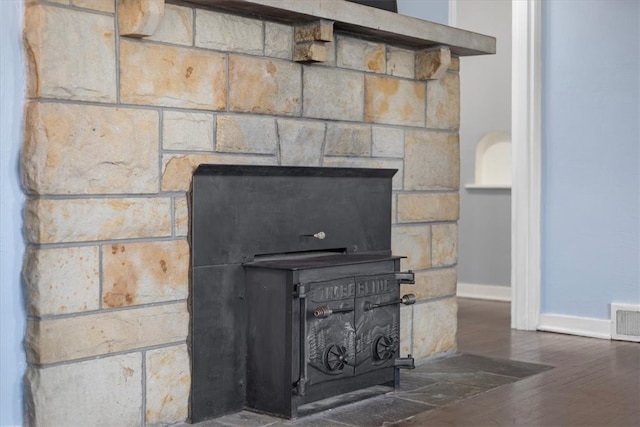 room details with a fireplace, hardwood / wood-style flooring, and a wood stove