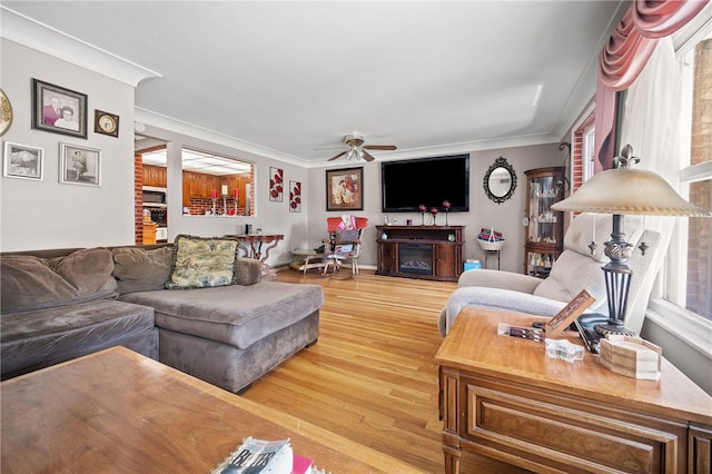 living room featuring light hardwood / wood-style flooring, a fireplace, brick wall, ceiling fan, and ornamental molding