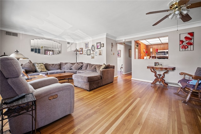 living room featuring a baseboard heating unit, crown molding, hardwood / wood-style floors, and ceiling fan