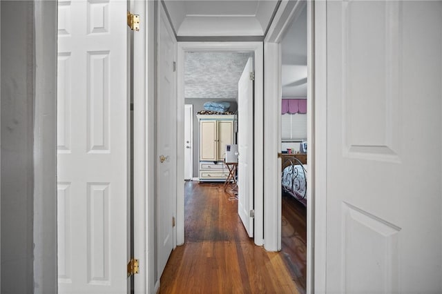 corridor with a textured ceiling and dark wood-type flooring