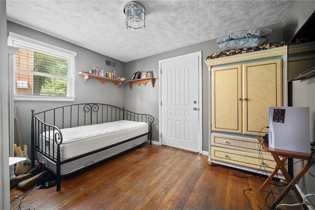 bedroom with dark hardwood / wood-style flooring and a textured ceiling