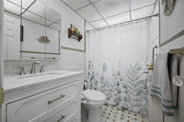 bathroom with vanity, tile walls, toilet, and tile patterned floors