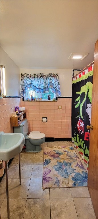 bathroom featuring tile patterned flooring, tile walls, and toilet