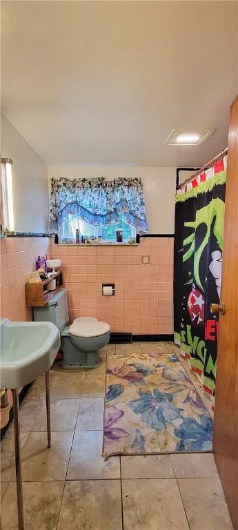 bathroom with tile patterned floors, toilet, and tile walls