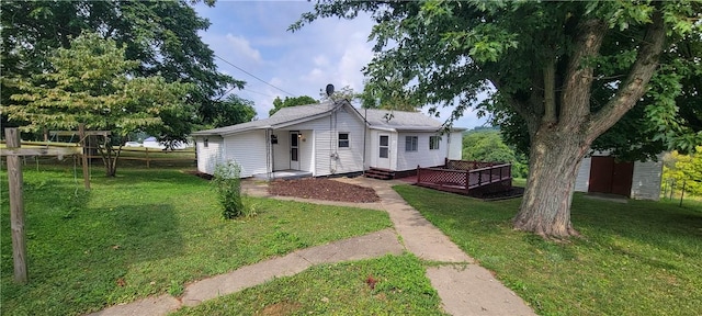 rear view of house with a wooden deck, a storage shed, and a lawn