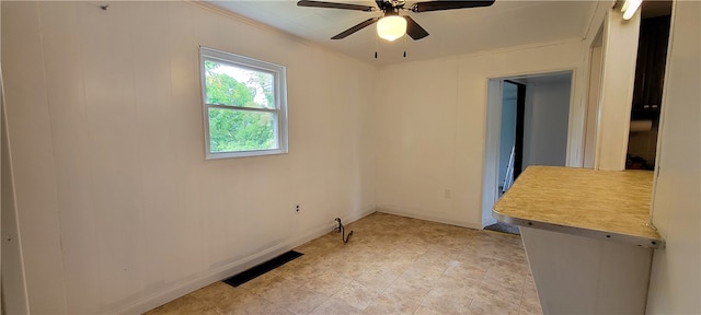 tiled empty room featuring ornamental molding and ceiling fan