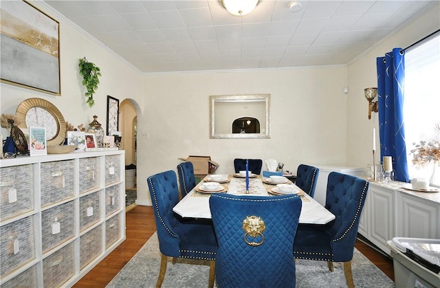 dining area featuring ornamental molding and dark wood-type flooring