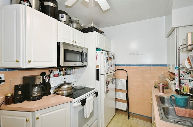 kitchen featuring sink, tile walls, white cabinets, ceiling fan, and white appliances